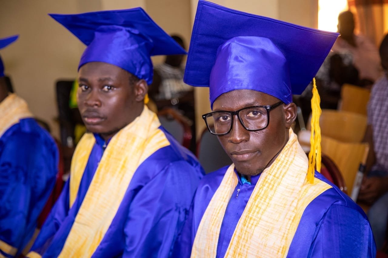 Deux jeunes diplômés en toge bleue et étole jaune assis côte à côte