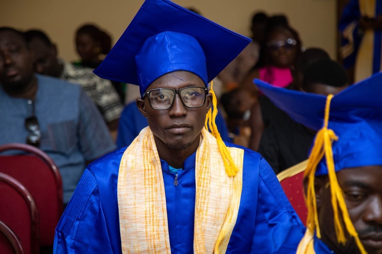 Un jeune diplômé à lunettes en toge bleue et étole jaune